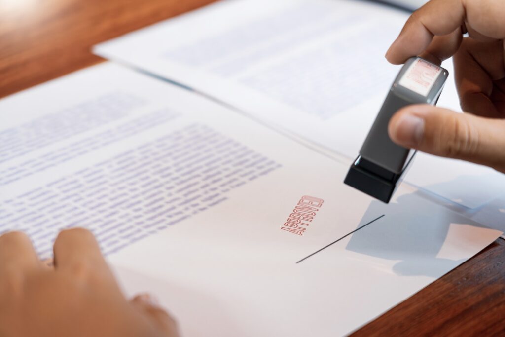 businessman hand notary public hand ink appoval stamper stamping seal on approved contract form.jpg