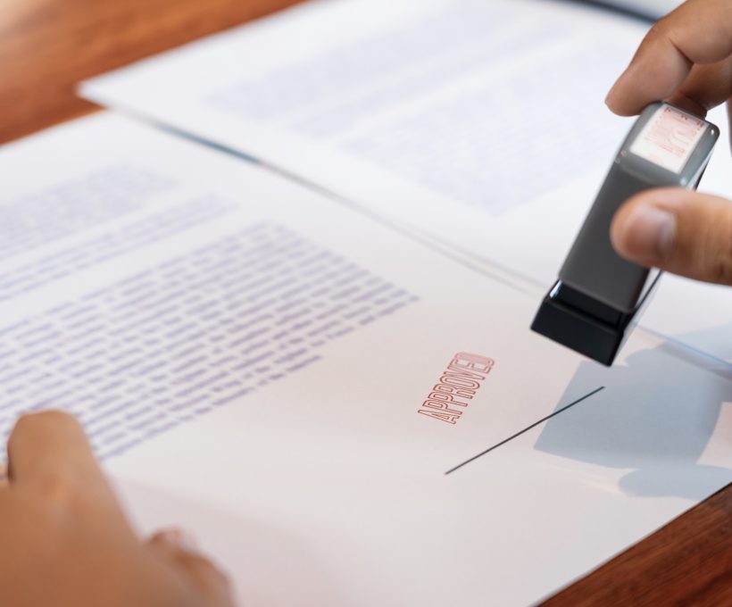 businessman hand notary public hand ink appoval stamper stamping seal on approved contract form.jpg